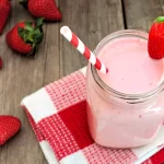 1-2 Taste IFF - Strawberry Liquid Flavour - 3397 Strawberry milkshake in a mason jar with red-striped straw and fresh strawberries on rustic wooden table