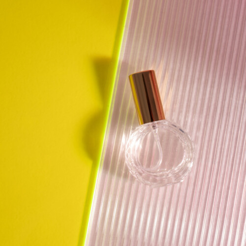 1-2 Taste IFF - New Matchless 222 Fragrance displayed in a round glass bottle with a metallic cap, set against a vibrant yellow and pink striped background