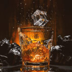 1-2 Taste IFF - Whisky Flavour - S 3031 displayed as a dramatic glass of whiskey with splashing ice cubes, surrounded by charred wood and a fiery background
