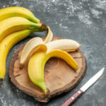 1-2 Taste IFF - Banana No.1 shown with ripe bananas and a peeled banana on a wooden board with a knife on a dark stone surface