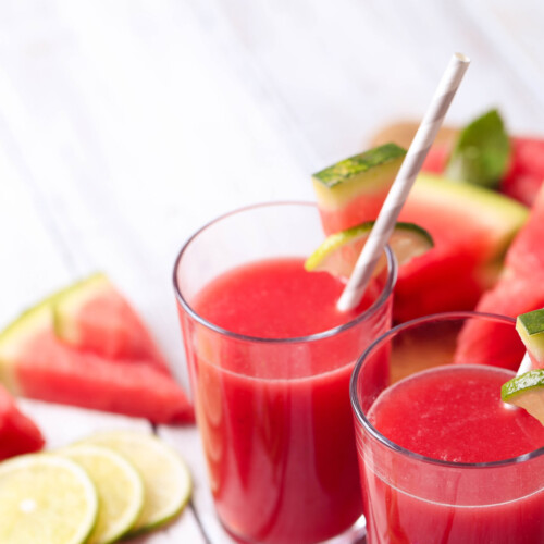 1-2 Taste IFF - Water Melon Flavour - S 3143 displayed as refreshing watermelon juice in glasses with lime slices and fresh watermelon wedges on a white wooden surface