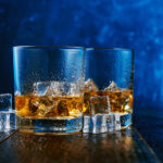 1-2 Taste IFF - Whisky Flavour Super presented as two whiskey glasses with ice cubes on a wet surface against a deep blue background