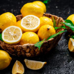 1-2 Taste IFF - Lemon Lime Flavour - S 3423 shown as Fresh yellow lemons in a woven basket with lemon slices and green leaves on a dark textured surface