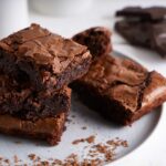 1-2 Taste Aroma INC - Chocolate Flavour Powder - O20207 shown as rich chocolate brownies stacked on a white plate with cocoa crumbs