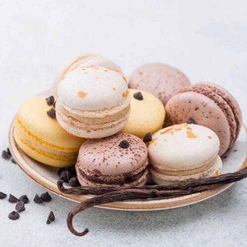 1-2 Taste Aroma INC - Vanilla Flavour Powder - O20206 shown as assorted vanilla and chocolate macarons on a plate with vanilla beans and chocolate chips
