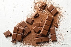 Tasty chocolate and powder on white background. Sweet food