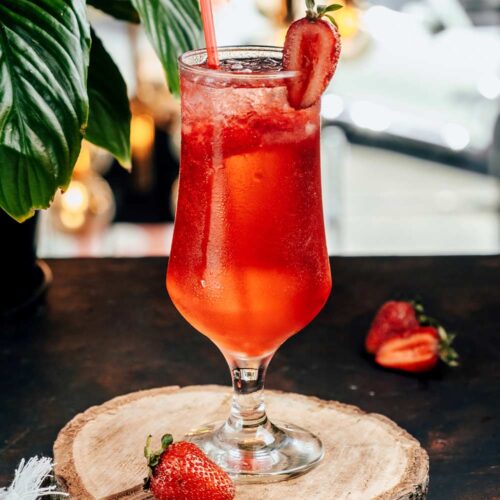 1-2 Taste Aroma INC - Strawberry Flavour Powder - O20209 shown as refreshing strawberry drink in a tall glass with sliced strawberries on wooden coaster