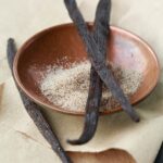 1-2 Taste Vanille BV - Organic Vanilla Powder in clay bowl with whole vanilla beans on parchment