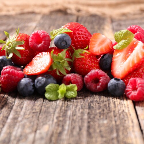 1-2 Taste Aroma INC - Natural Forest Fruit Flavour Liquid - O20203 shown as Mixed berries including strawberries, raspberries, and blueberries on rustic wooden surface