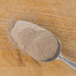 1-2 Taste Blonk Quality Ingredients - Teff Flour Instant Brown shown as Spoonful of fine brown teff flour on a wooden surface