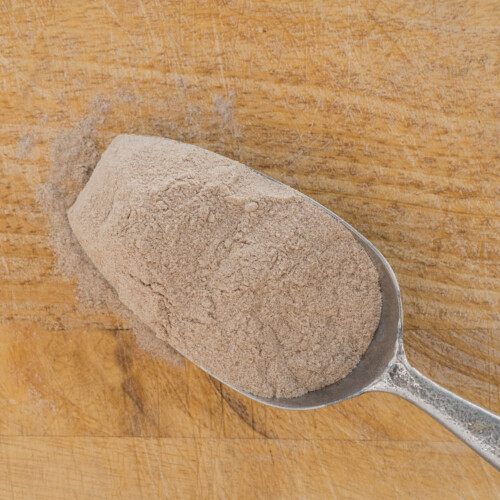 1-2 Taste Blonk Quality Ingredients - Teff Flour Instant Brown shown as Spoonful of fine brown teff flour on a wooden surface