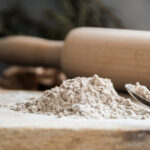 1-2 Taste Blonk Quality Ingredients - Organic Teff Grain White shown as pile of fine white teff flour on wooden surface with rolling pin in background