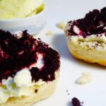 Nutracevit - Organic Haskap Berry Powder (Lonicera caerulea)- POHB as Scones topped with cream and organic haskap berry powder (Lonicera caerulea) on white surface