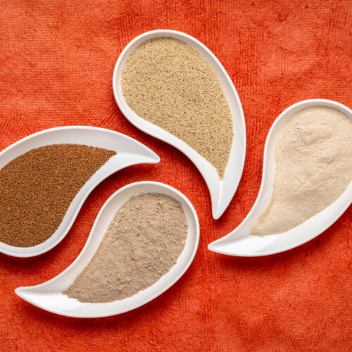 1-2 Taste Blonk Quality Ingredients - Teff Flour Fine Brown shown as assorted teff flour varieties in elegant white dishes on a vibrant orange background