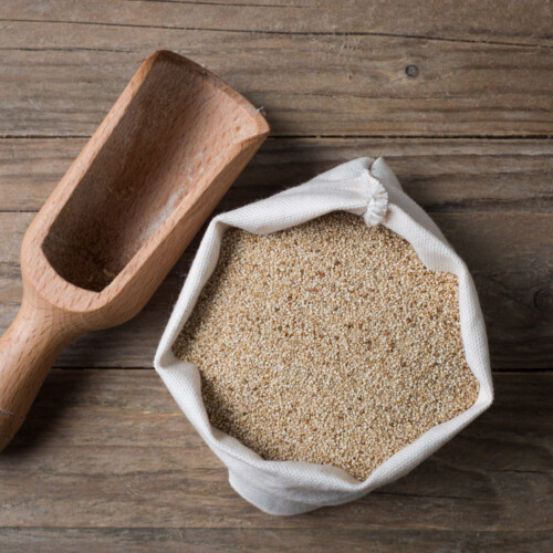 1-2 Taste Blonk Quality Ingredients - Organic Teff Flour Brown shown as sack of brown teff flour with wooden scoop on rustic wooden table