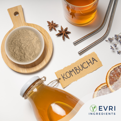 1-2 Taste EVRI Ingredients - Kombucha Soluble Powder - 100050 displayed with a bowl of light beige powder, kombucha drink in a glass, a labeled bottle, star anise, and dried citrus slices on a white background