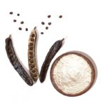1-2 Taste Sarda Bio Polymers – LBG Carcol 25A Locust Bean Gum powder with carob pods and seeds on white background