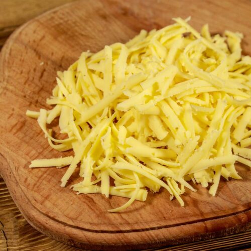 1-2 Taste Trigona - Gouda 48+ grated cheese on wooden cutting board