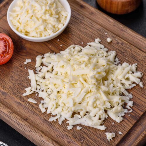 1-2 Taste Trigona - Mozzarella 40+ grated cheese on wooden cutting board and in white bowl