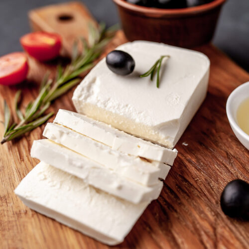 1-2 Taste Trigona - Feta Greece Origin, creamy white blocks and slices on wooden board with olives and herbs