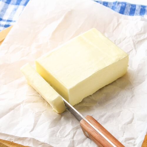 1-2 Taste Trigona - Lactic Butter block sliced with wooden-handled knife on parchment paper