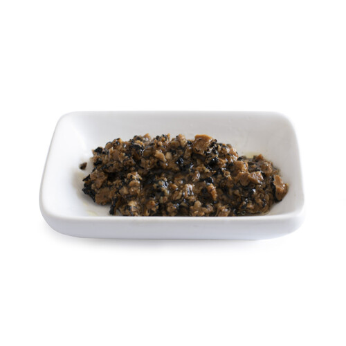 Trufo – Black Summer Truffle Brisure 7% displayed on a white rectangular dish, showing a coarse blend of chopped truffles with a moist, textured appearance