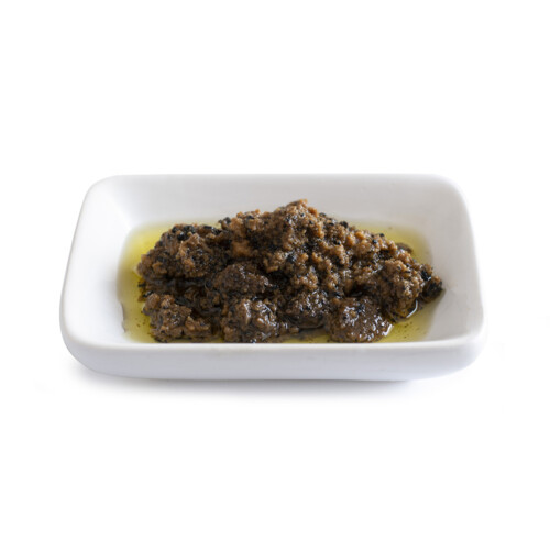 Trufo – Black Summer Truffle Sauce in Oil served on a white rectangular dish, showcasing a rich, chunky blend of truffle pieces in golden olive oil