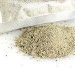 Trufo - Freeze Dried Truffle Powder spilled from a transparent vacuum-sealed pouch onto a white surface, showcasing its fine, dry texture