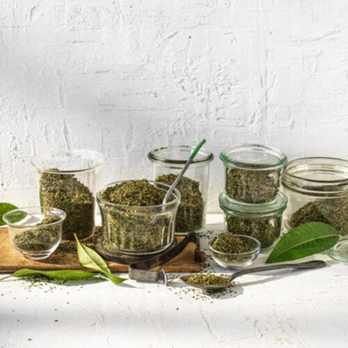 Lemon Myrtle Dried Leaf Medium Cut in glass containers with green leaves, USDA Organic certified