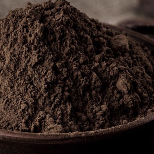 1-2 Taste JS Cocoa – Mildly Alkalized Cocoa Powder UMBRA™, displayed as a heaped mound of rich brown cocoa powder in a dark ceramic bowl with soft lighting
