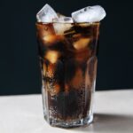 1-2 Taste Aroma INC - Cola Flavour - O20233 shown as Glass of chilled cola with ice cubes on a dark background