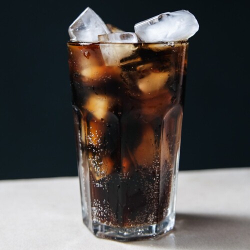 1-2 Taste Aroma INC - Cola Flavour - O20233 shown as Glass of chilled cola with ice cubes on a dark background