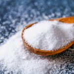 1-2 Taste NuTek Natural Ingredients - Salt for Life 100 RF G3 Standard - 14510 shown as Fine white salt crystals in a wooden spoon on a dark textured surface