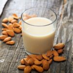 1-2 Taste Vegan Stock - Roasted Blanched Almond Milk Base - RBAPBA1EU107.A9 shown as a glass of almond milk with roasted blanched almonds on rustic wooden surface