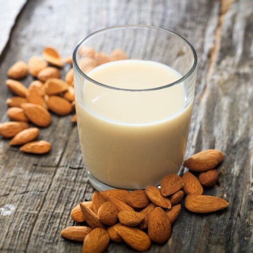 1-2 Taste Vegan Stock - Roasted Blanched Almond Milk Base - RBAPBA1EU107.A9 shown as a glass of almond milk with roasted blanched almonds on rustic wooden surface